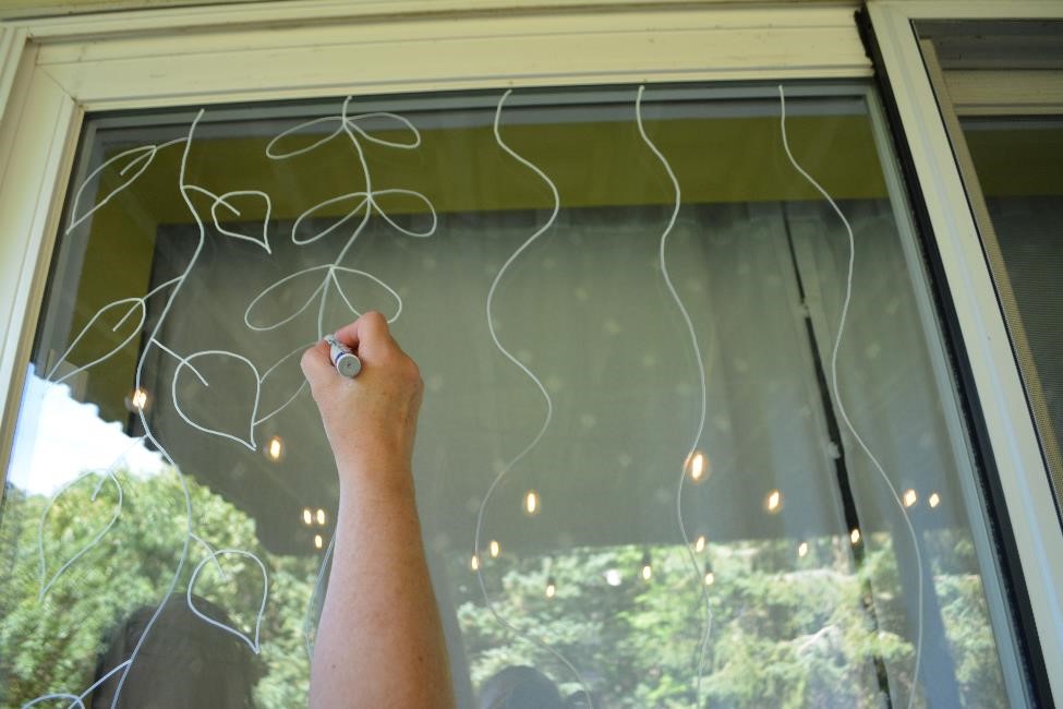 Drawing leaves on wavy lines to create hanging vines on a window.